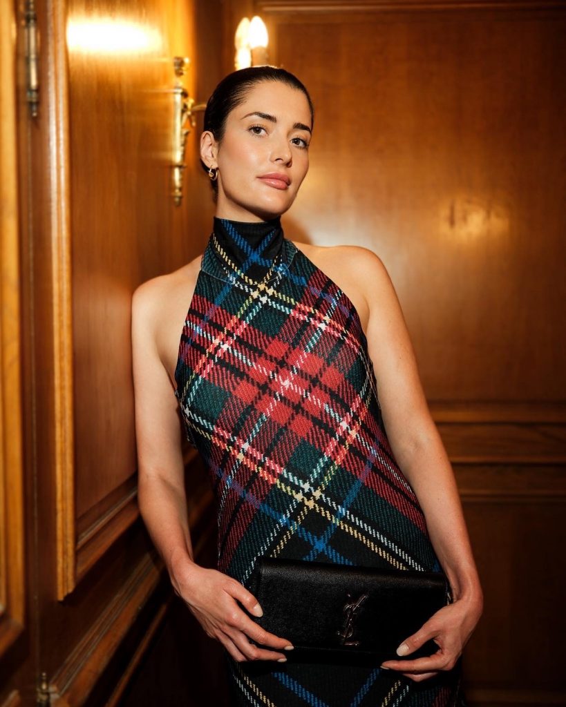 Fashion stylist Alina Barchet wearing a Norma Kamal dress with tartan pattern and a Saint Laurent clutch bag. Tartan pattern is one of the key fashion trends for winter 2023 / 2024.