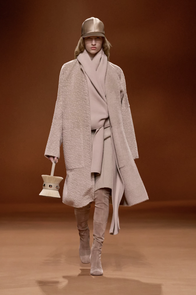 Hermès Runway look in rosé beige, one of the key fashion trends for fall-winter. The model is holding a bucket bag in her hand another major trend of the upcoming season.