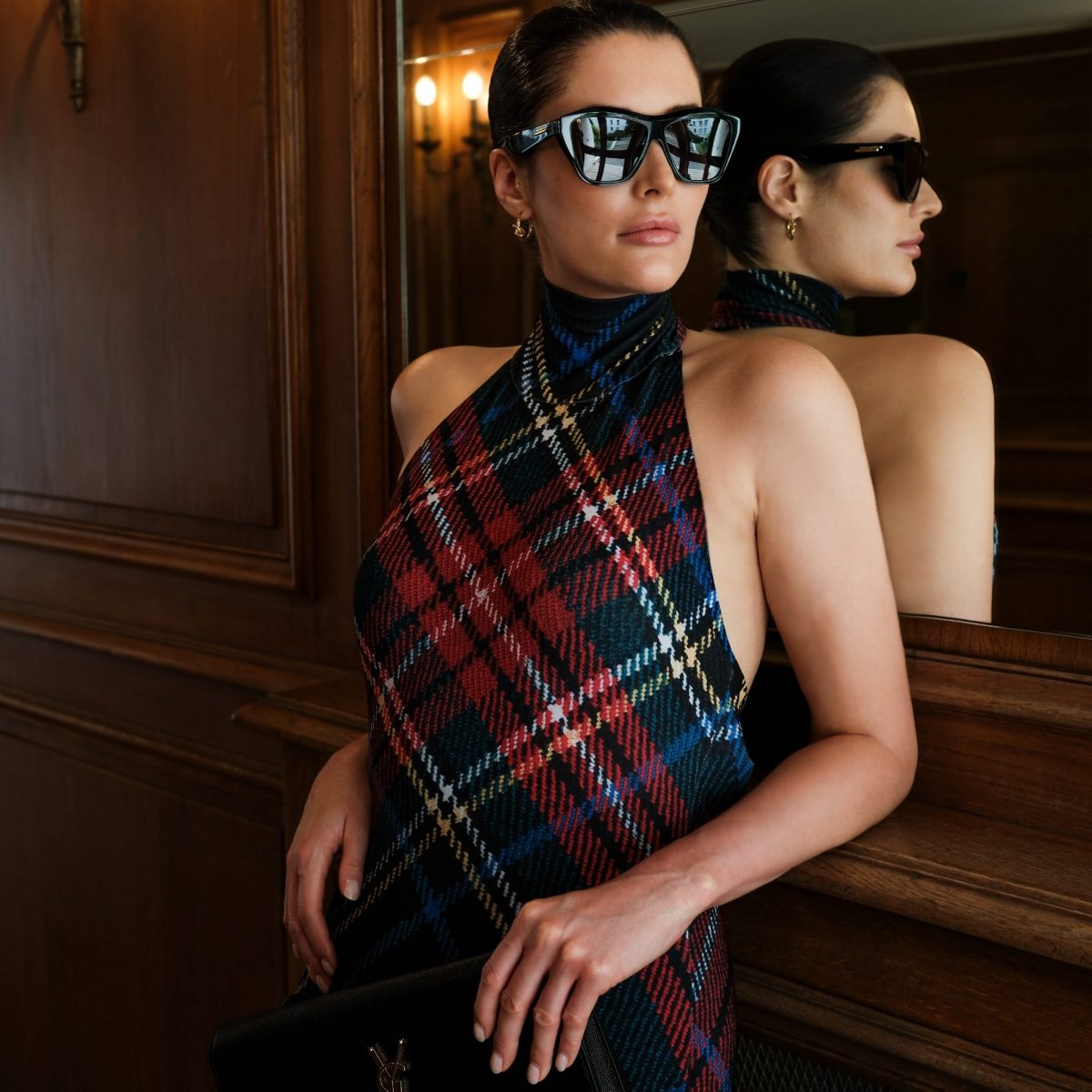 Fashion expert and stylist Alina Barchet wears a Norma Kamali dress with tartan pattern, black Bottega Veneta sunglasses with golden accents, a black clutch from Saint Laurent and small, golden Celine Knot hoop earrings. Alina Barchet styled the outfit for a photo shooting in Paris.